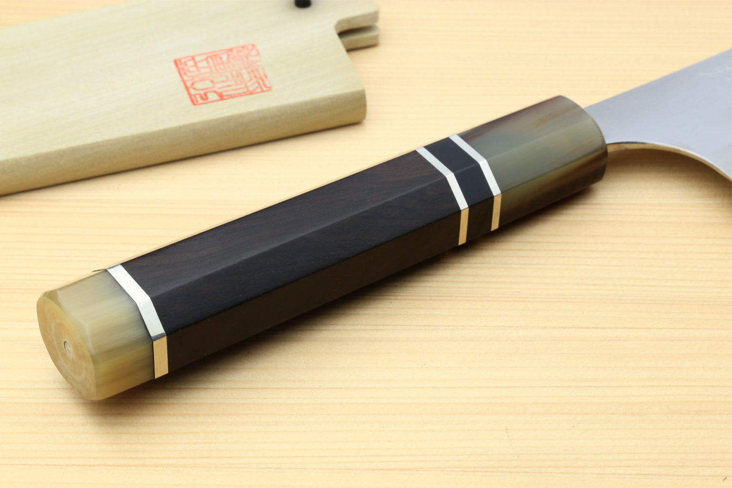 Gyuto chef knife straight-on handle view with dark ebony scales and triple ring accents
