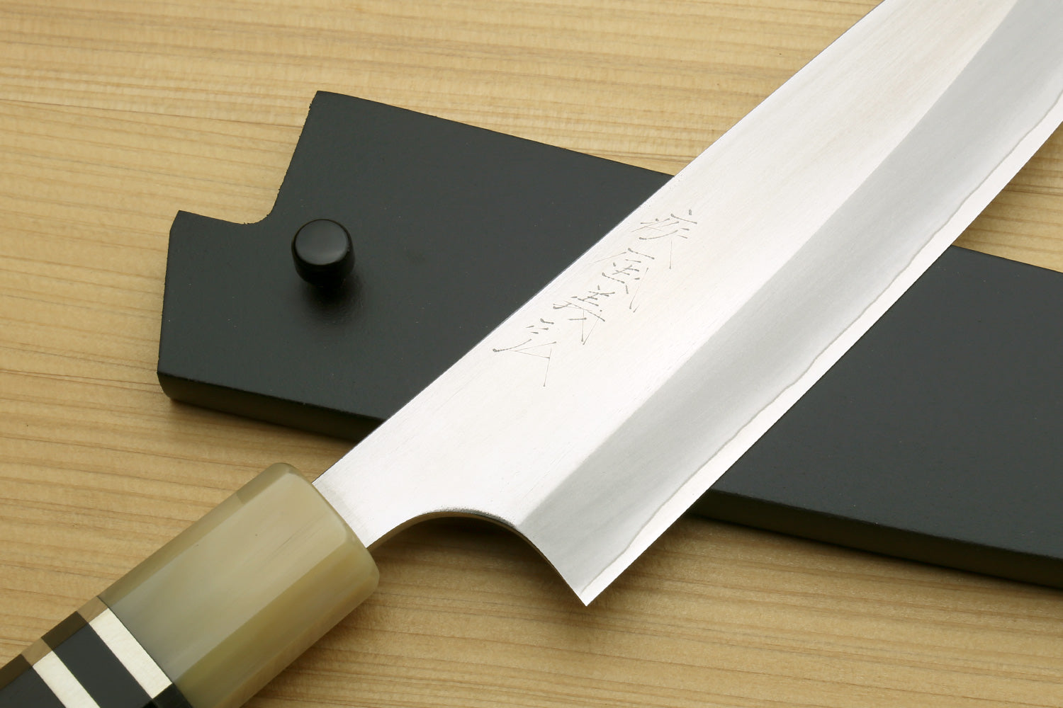 Petty utility chef knife close-up of stainless blade edge and dark handle with ring accents