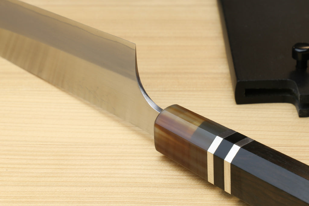 Petty utility chef knife close-up of blade tip and dark handle with ring bands