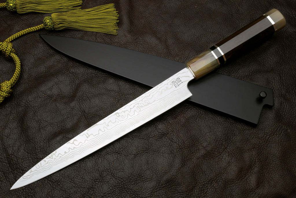 Sujihiki slicer knife, long damascus blade with dark handle, shown from side angle