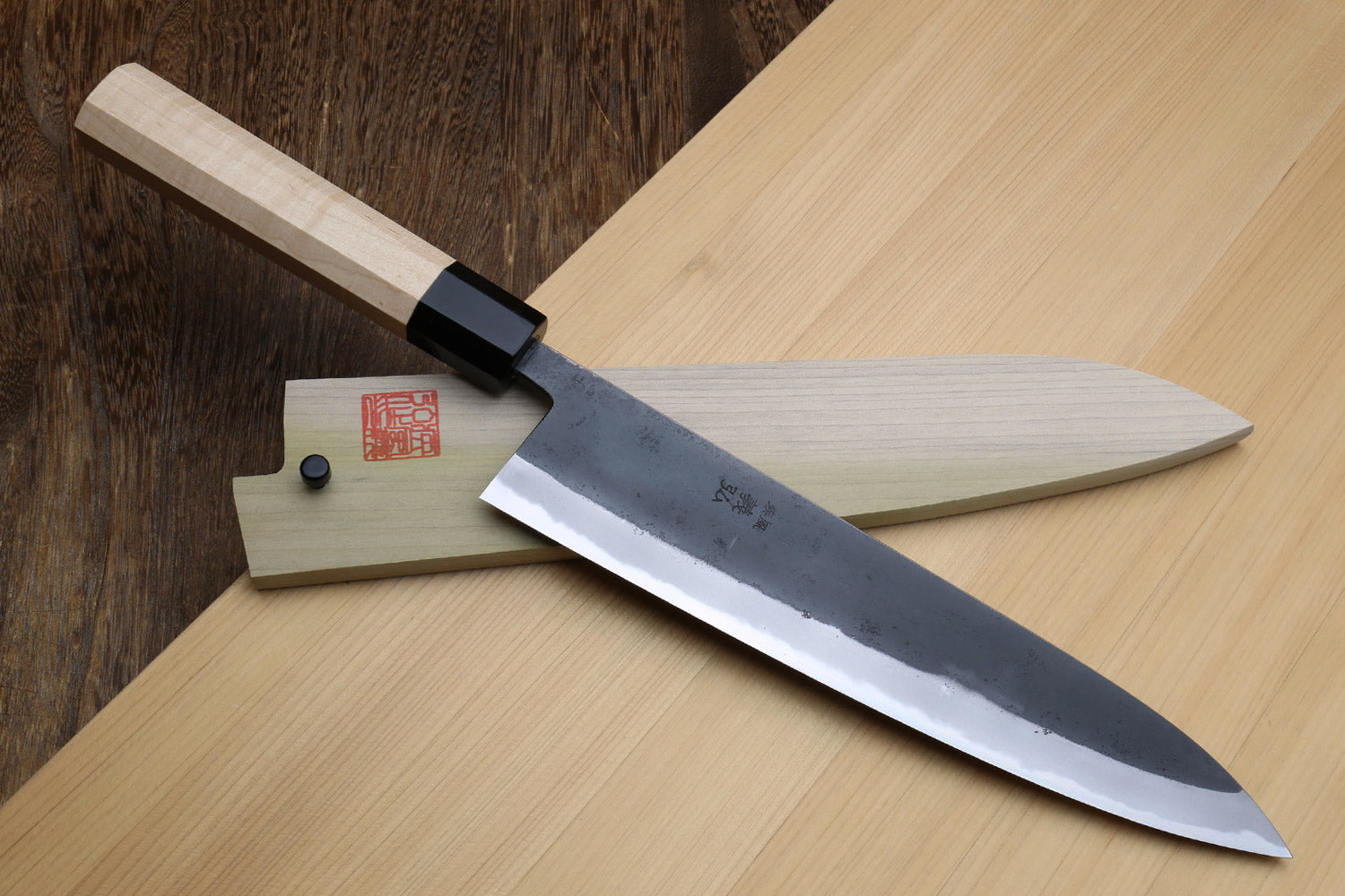 Kurouchi blue steel gyuto knife with light Kaede handle, black collar, and etched blade