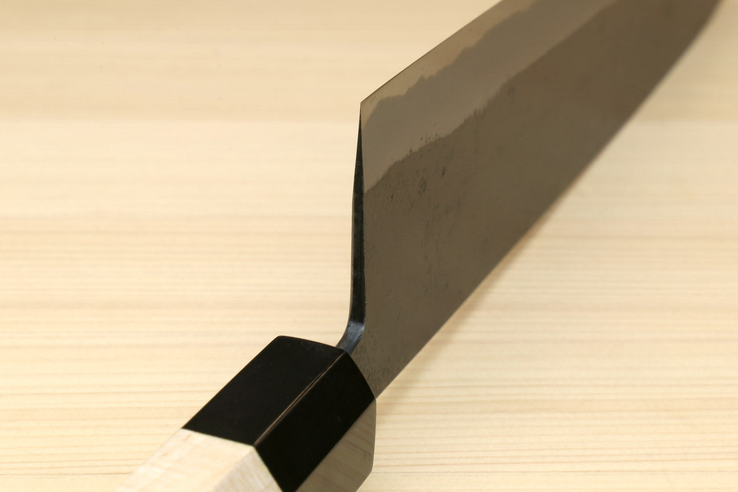 Gyuto knife with light wood handle and black sheath cover over the blade heel