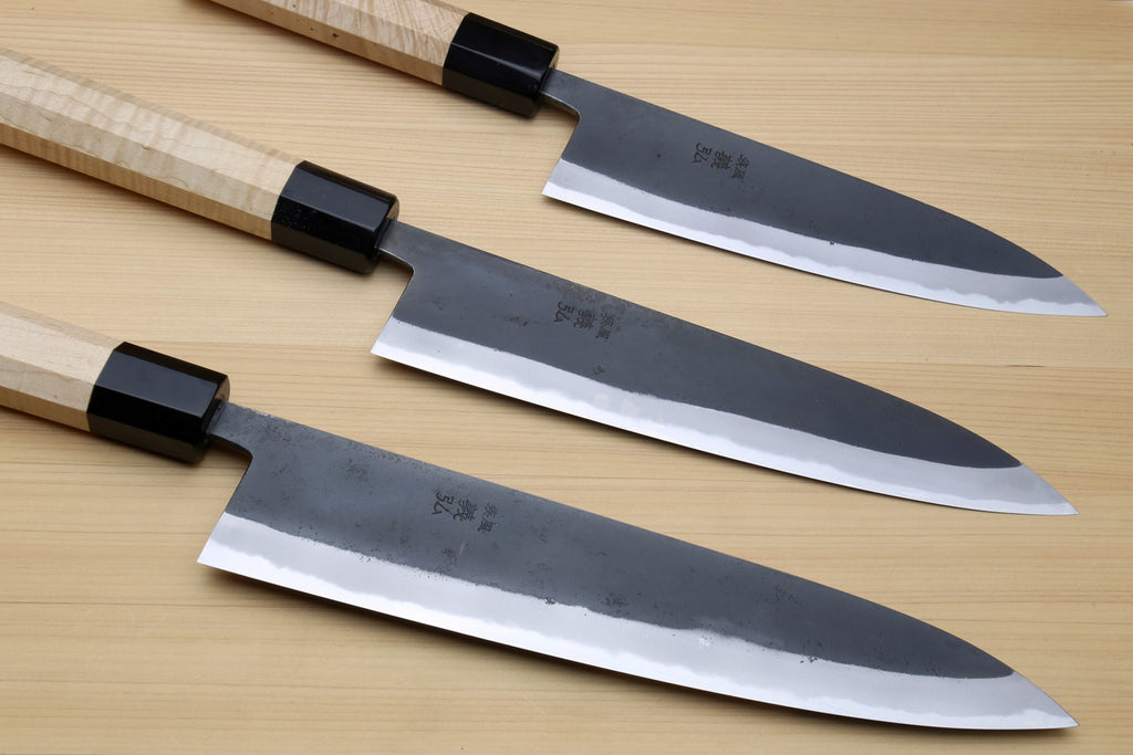 Set of blue steel kurouchi gyuto knives with light Kaede handles and black collars