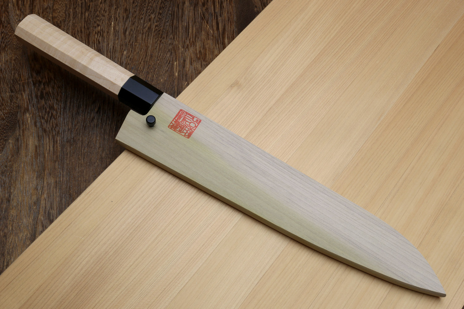 Blue steel kurouchi gyuto knife with light Kaede handle, black collar, and logo stamp