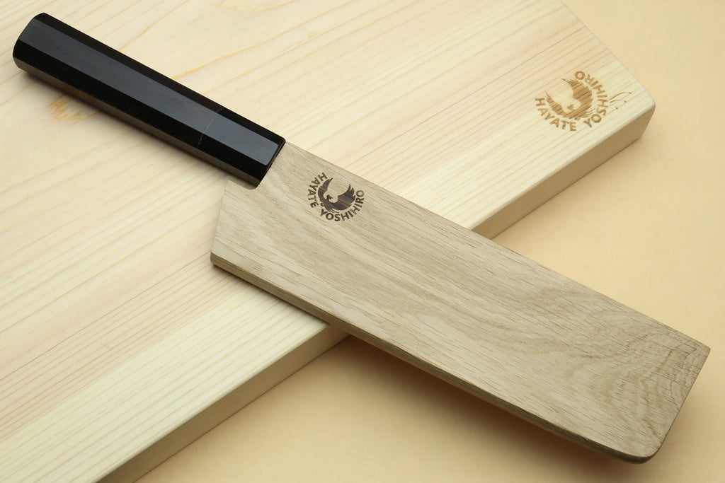 Nakiri knife with black handle and blue-steel blade on light wooden stand