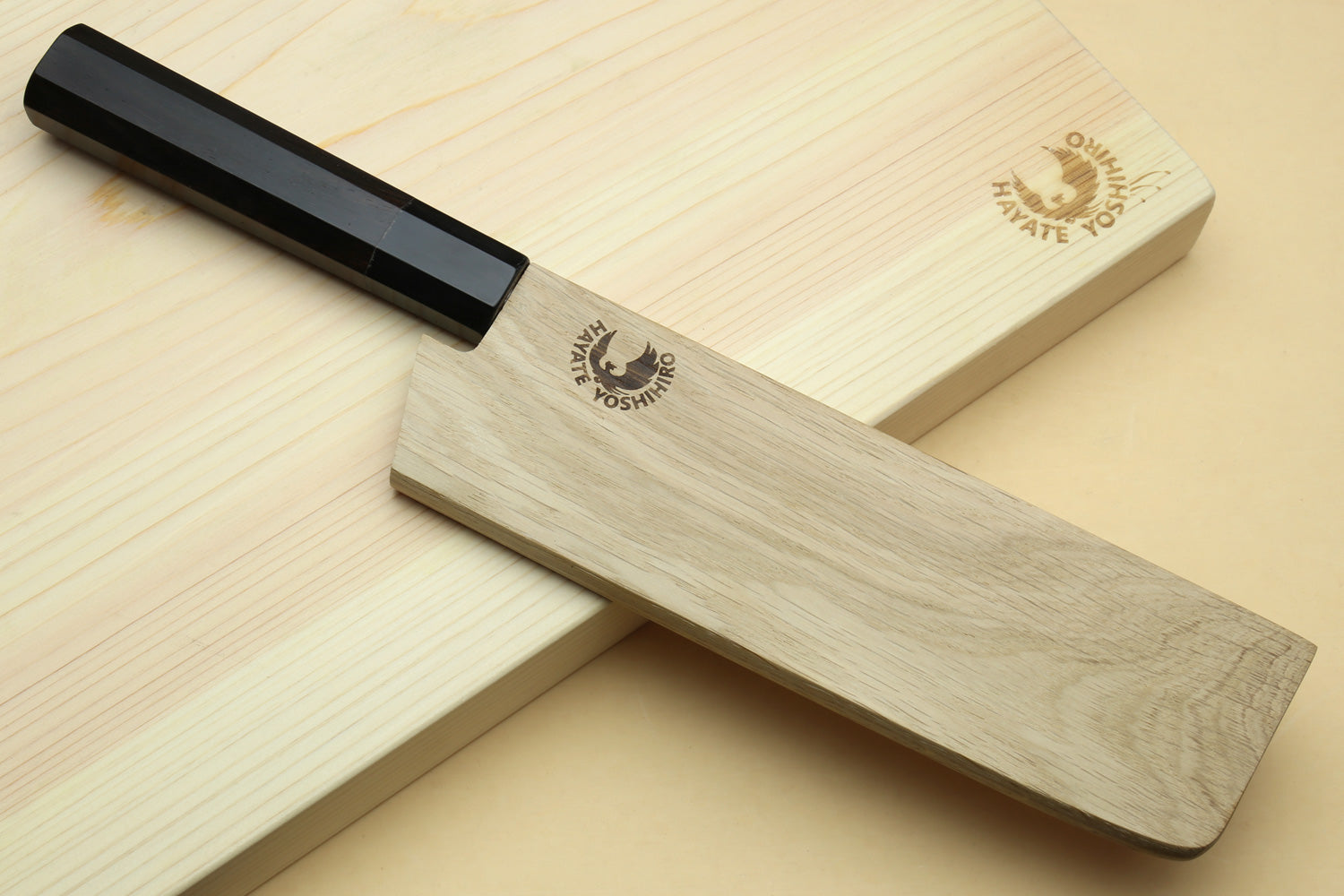 Nakiri knife with black handle and blue-steel blade on light wooden stand