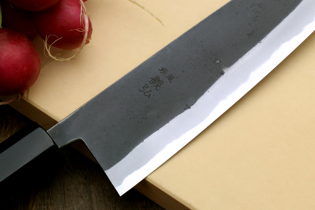 Santoku knife close-up of dark blade with etched markings and shiny edge
