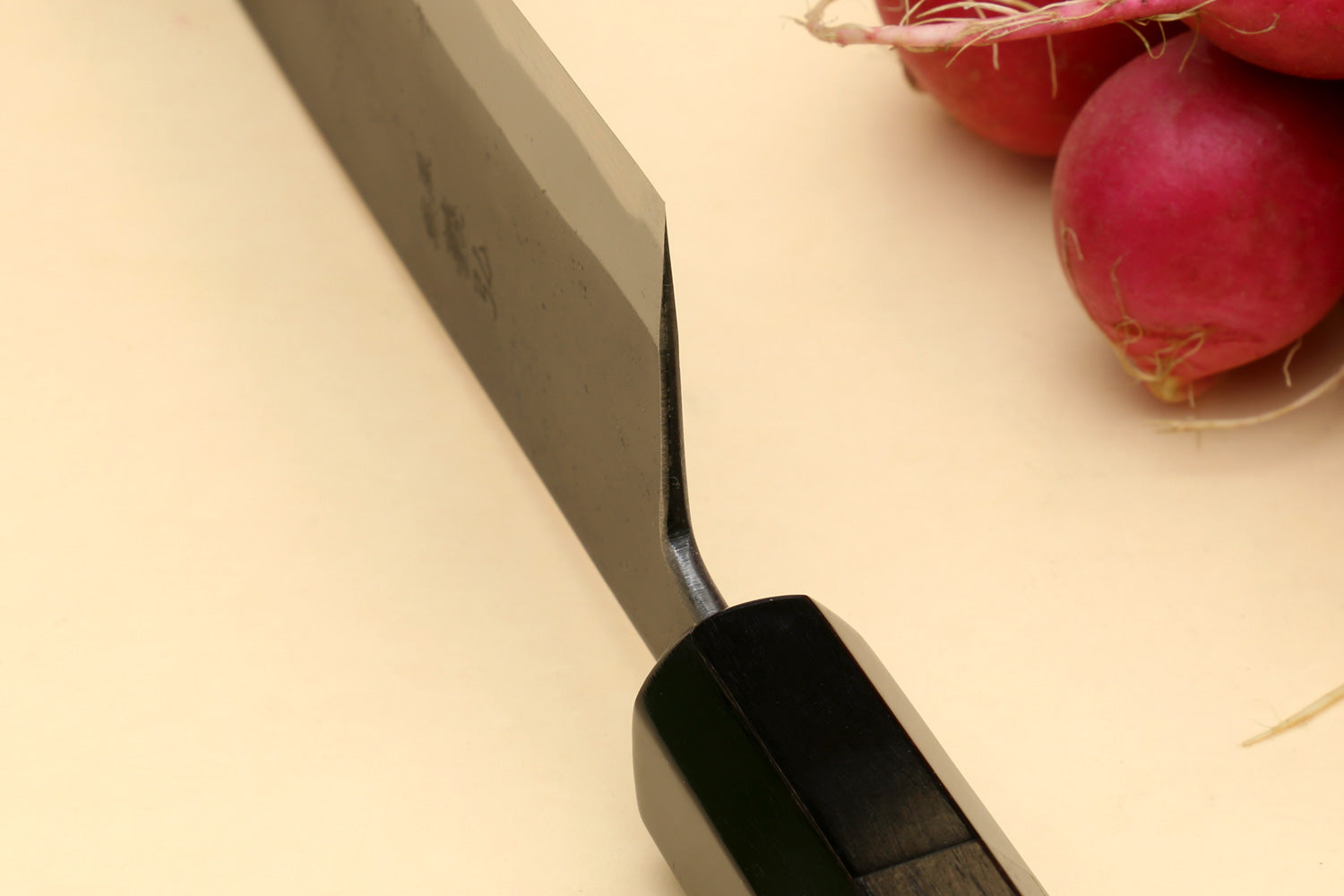 Santoku knife handle close-up with dark wooden grip and metal end
