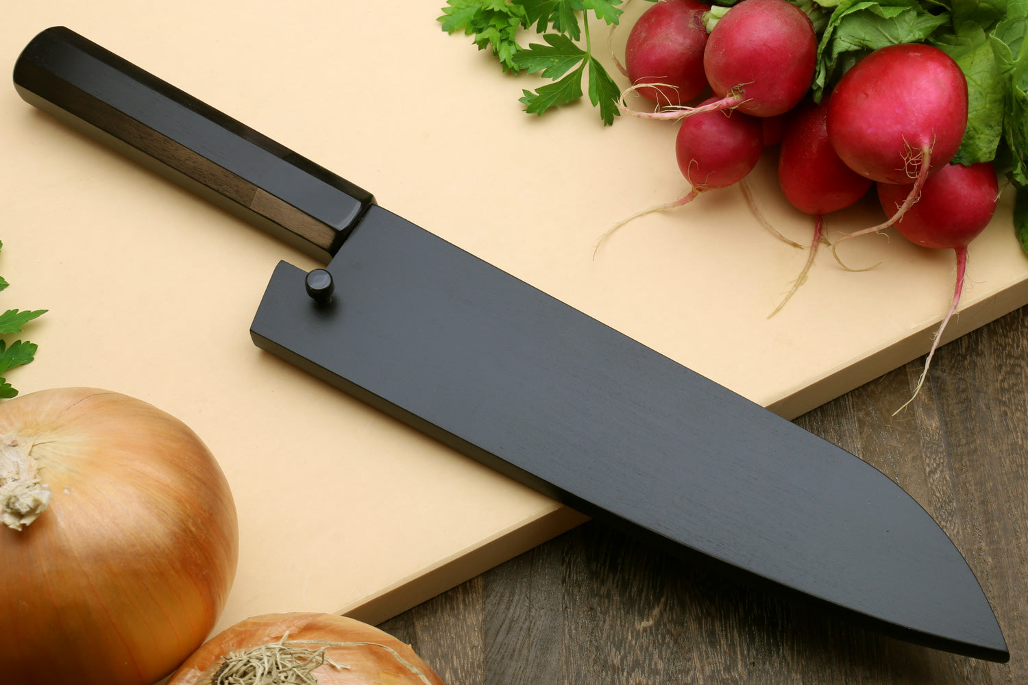 Santoku knife with dark blade and black handle cover on a cutting surface