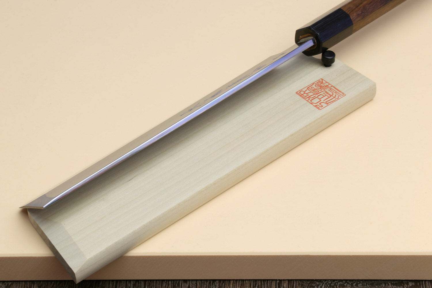 Japanese vegetable cleaver knife with blue steel blade and rosewood handle on light saya