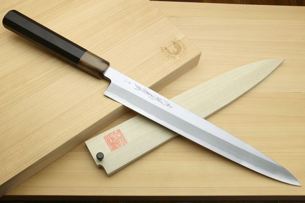 Yanagi sushi knife with white blade, dark handle, and wooden saya