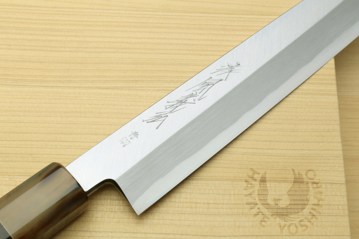 Yanagi sushi knife blade close-up with Japanese engravings on white steel