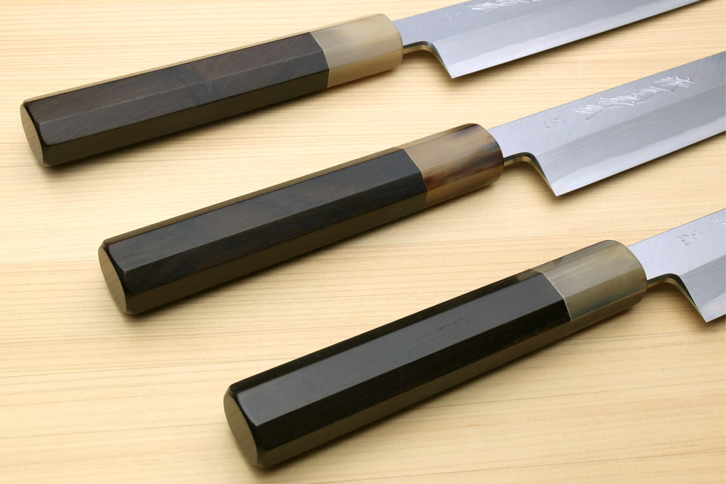 Set of three Yanagi sushi knives with dark handles and white blades