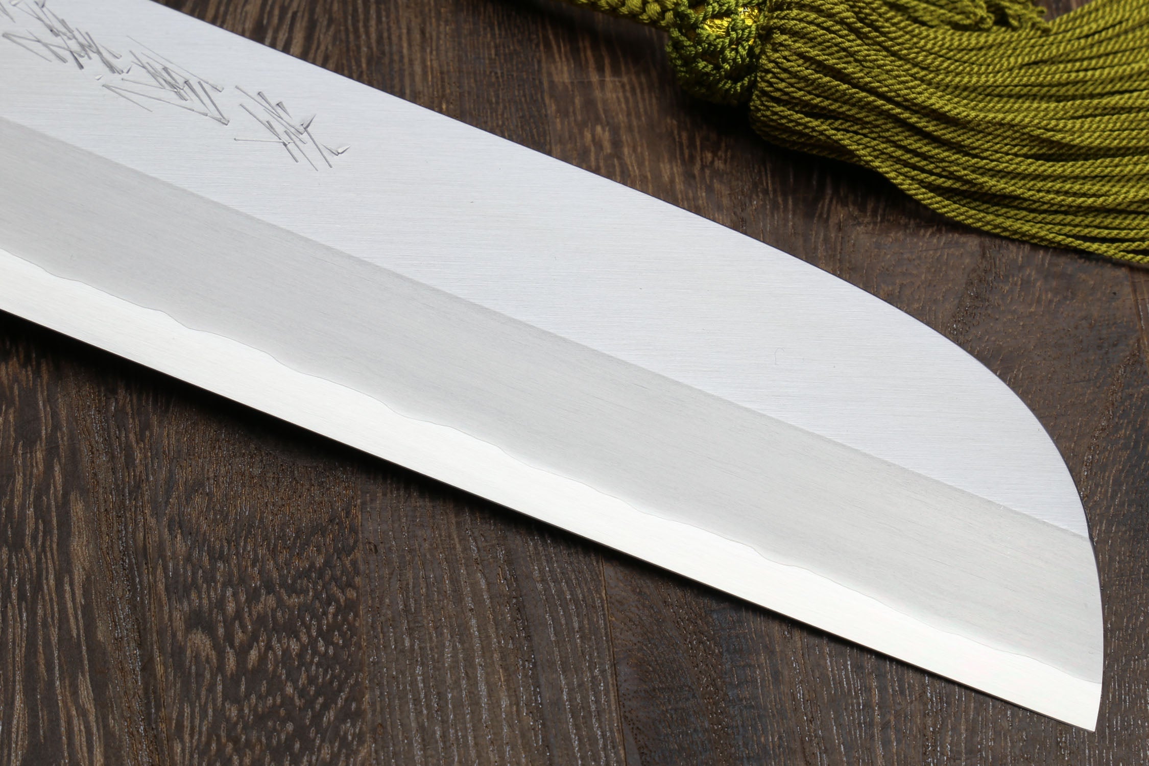 Japanese kama usuba knife blade tip with light finish and curved edge, close-up.