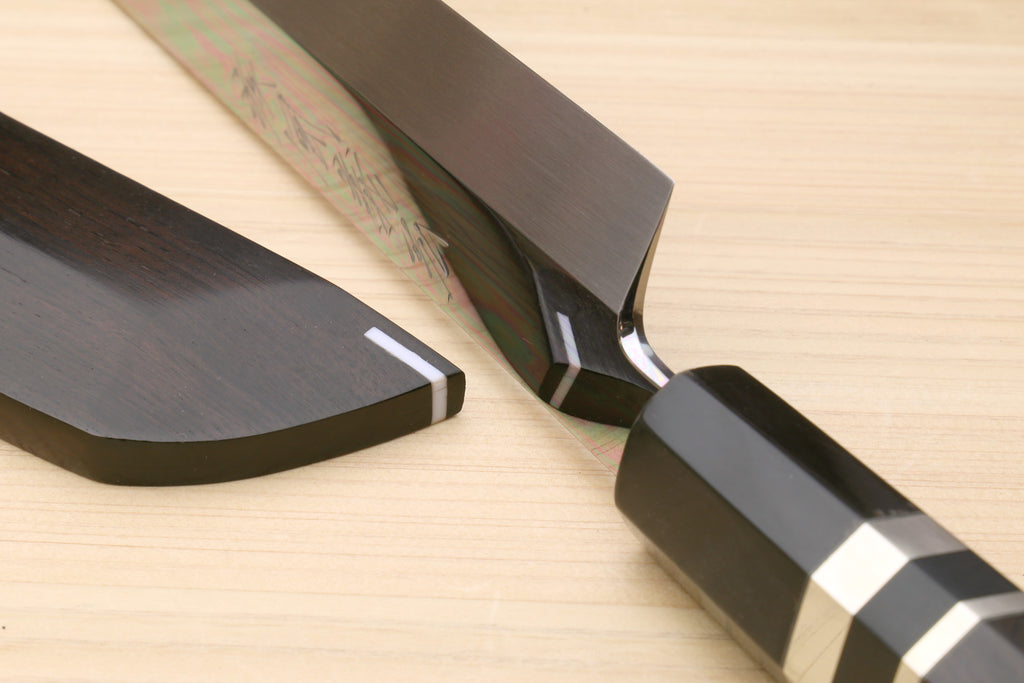 Japanese sushi knife blade with dark edge and ebony saya on light wood board