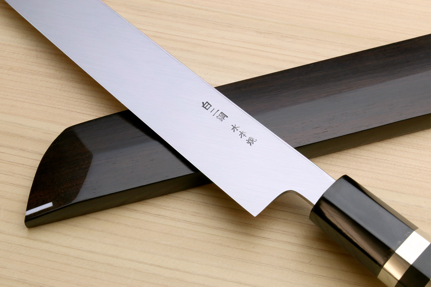 Japanese sushi knife with mirror-finished white blade, ebony handle, and saya