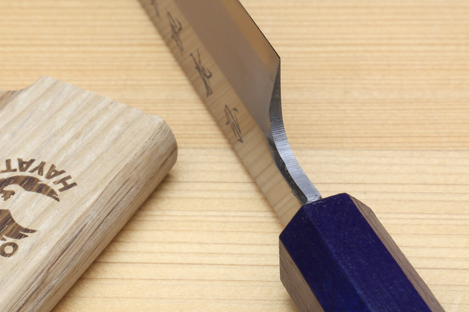 Yanagi sushi knife edge close-up with dark-blue handle and wooden saya cover