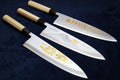 Set of three deba fish fillet knives with white blades and gold etching, wood handles