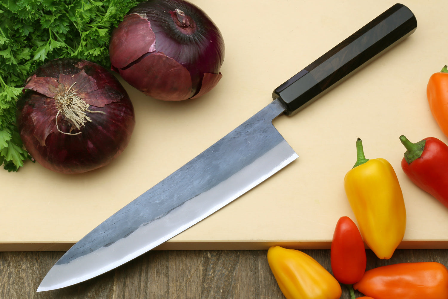 Chef knife with a black handle and long silver stainless blade on a cutting board.