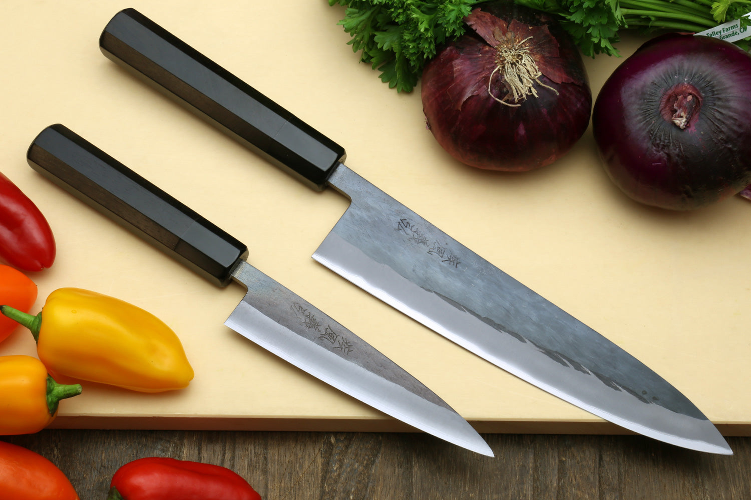 Two kitchen knives with black handles and silver stainless blades, side-by-side.