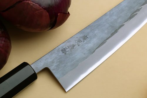 Gyuto chef's knife blade close-up with engraved markings and black handle