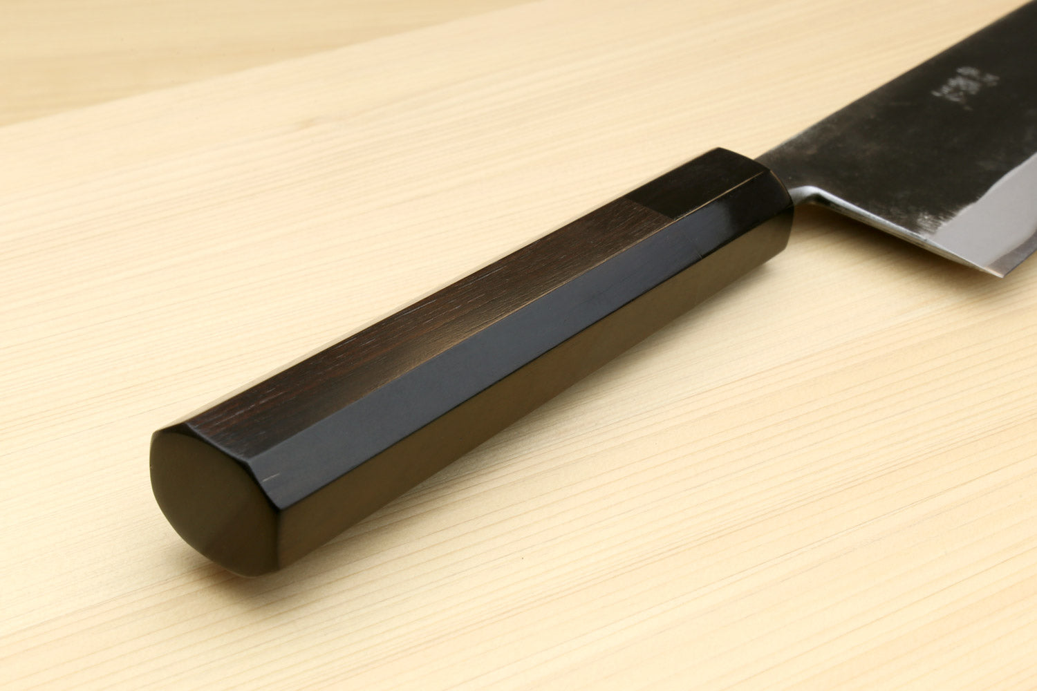Kiritsuke chef knife handle close-up, ebony grip on dark blue steel blade
