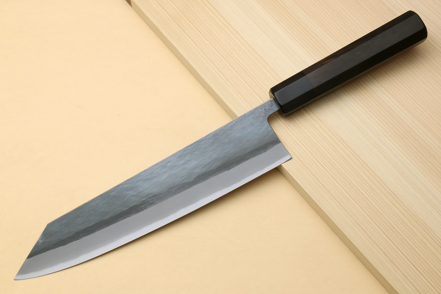 Kiritsuke chef knife with ebony handle, blue-gray blade on cutting board