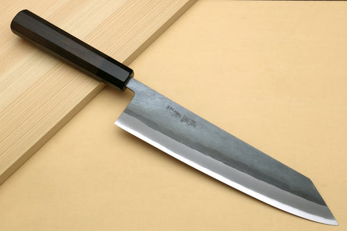 Kiritsuke chef knife, ebony handle and blue-gray blade laid on board