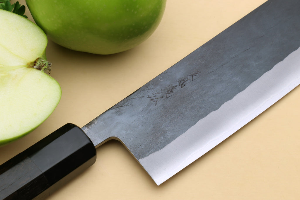 Nakiri knife close-up of black handle and wide blue-steel clad blade