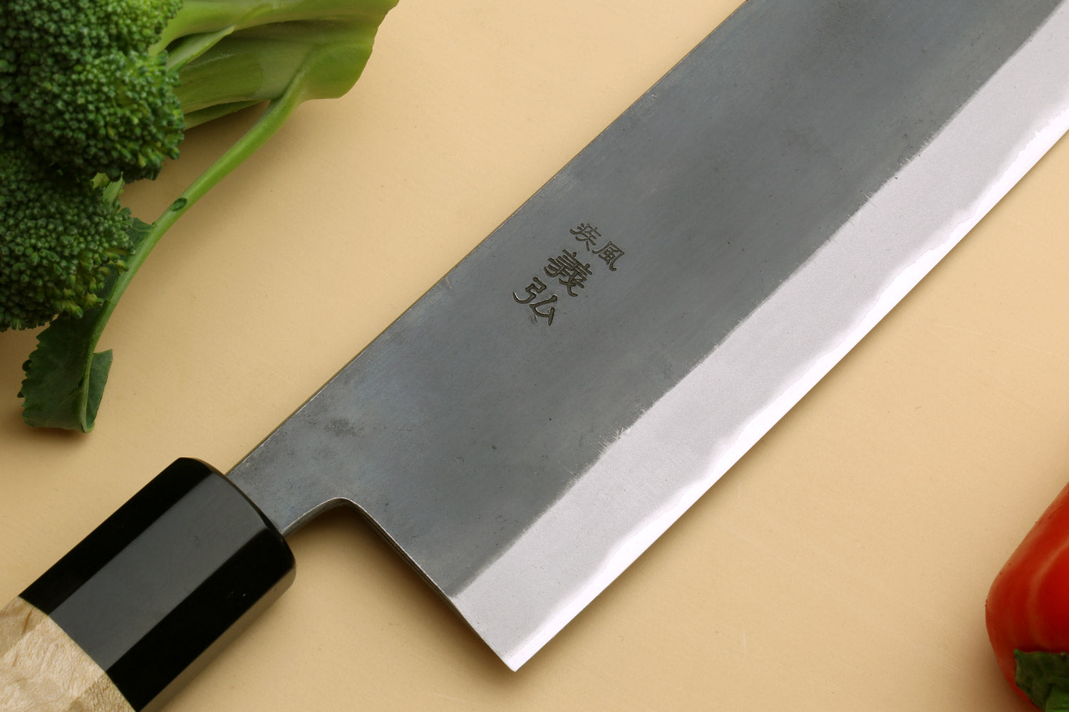 Nakiri knife close-up of blade and tang, black handle, gray steel surface