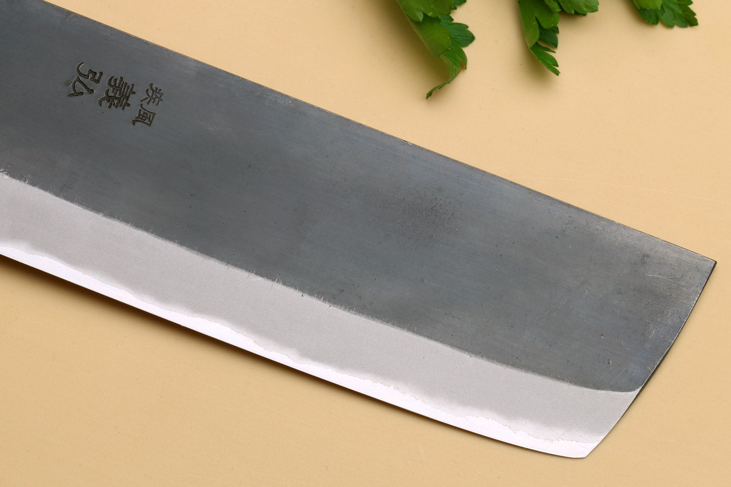 Nakiri knife blade close-up showing etched characters on gray steel
