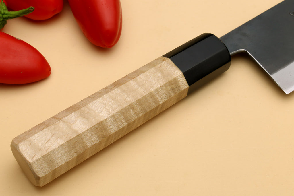 Nakiri knife handle close-up, light wood grip with black bolster and gray blade