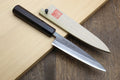Petty utility knife with dark ebony handle and stainless blade, on wood board