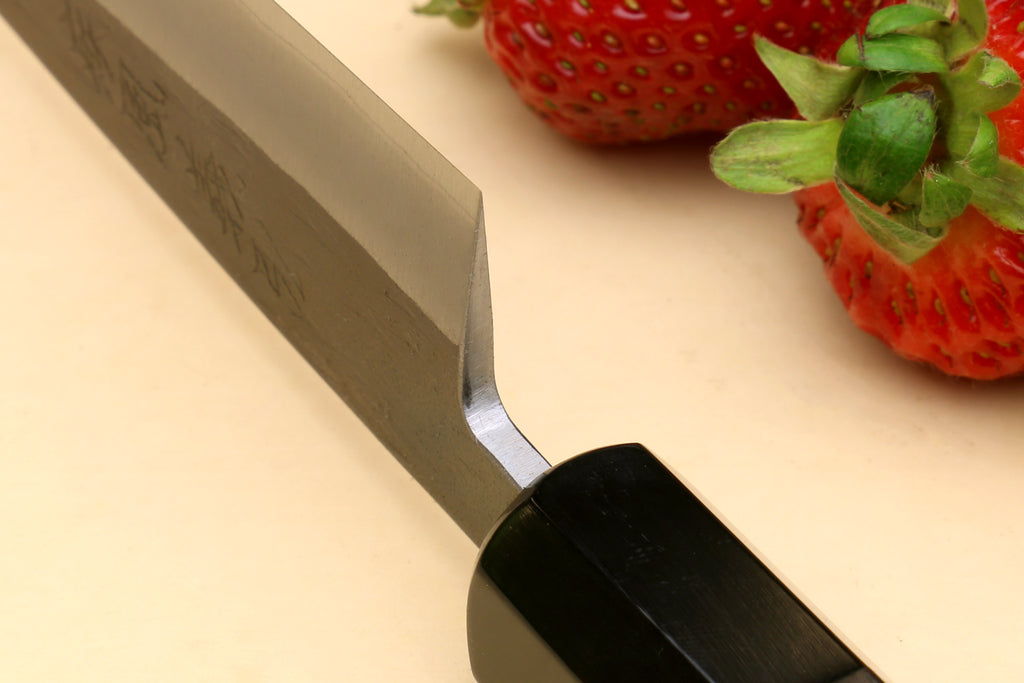 Petty utility knife with stainless blade and dark ebony handle, bolster and curve close-up
