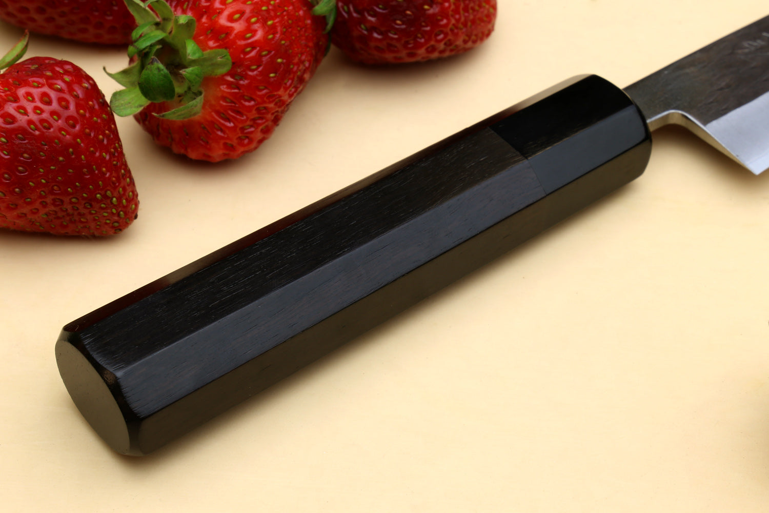 Petty utility knife with dark ebony handle and stainless blade, handle end close-up