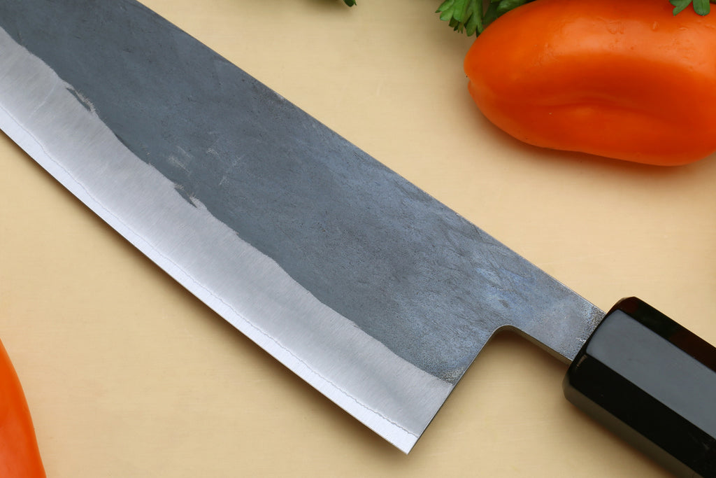 Ebony-handled santoku knife blade close-up, sharp tip and cutting edge visible