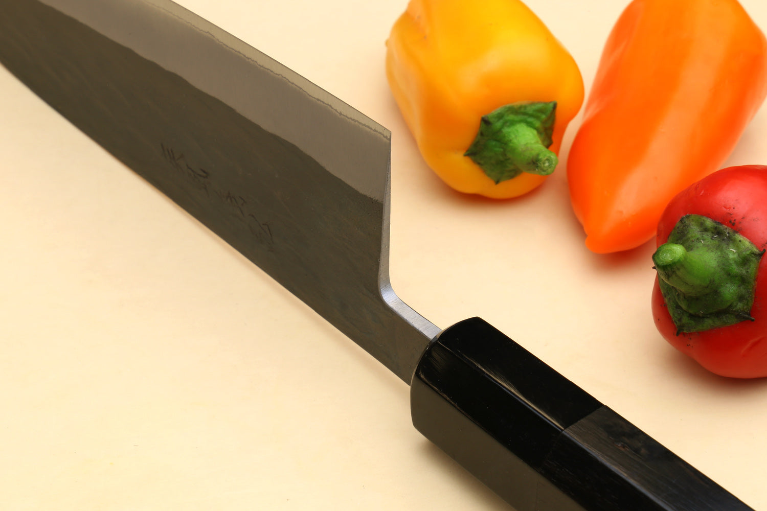 Ebony-handled santoku knife with dark spine and silver blade, angled view