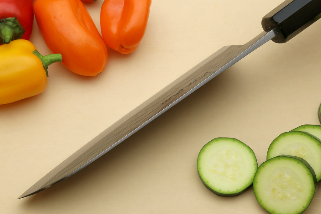 Santoku knife with light wood handle, edge and pointed tip shown