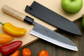 Santoku knife with stainless blade and black sheath on board