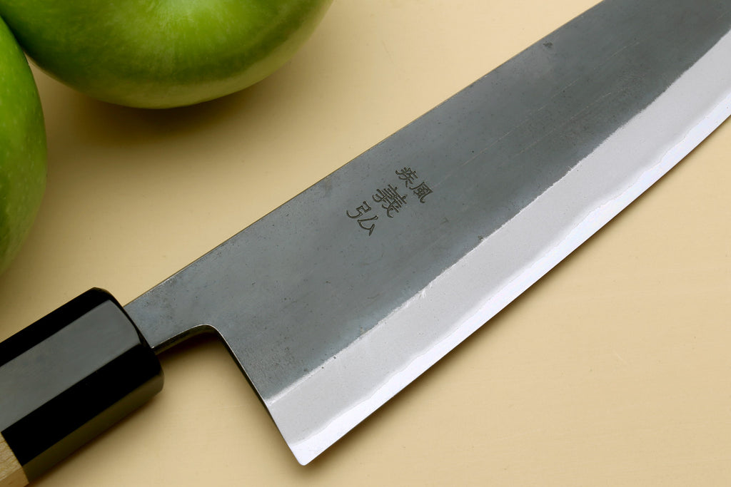 Santoku knife blade close-up with stamped markings and black bolster