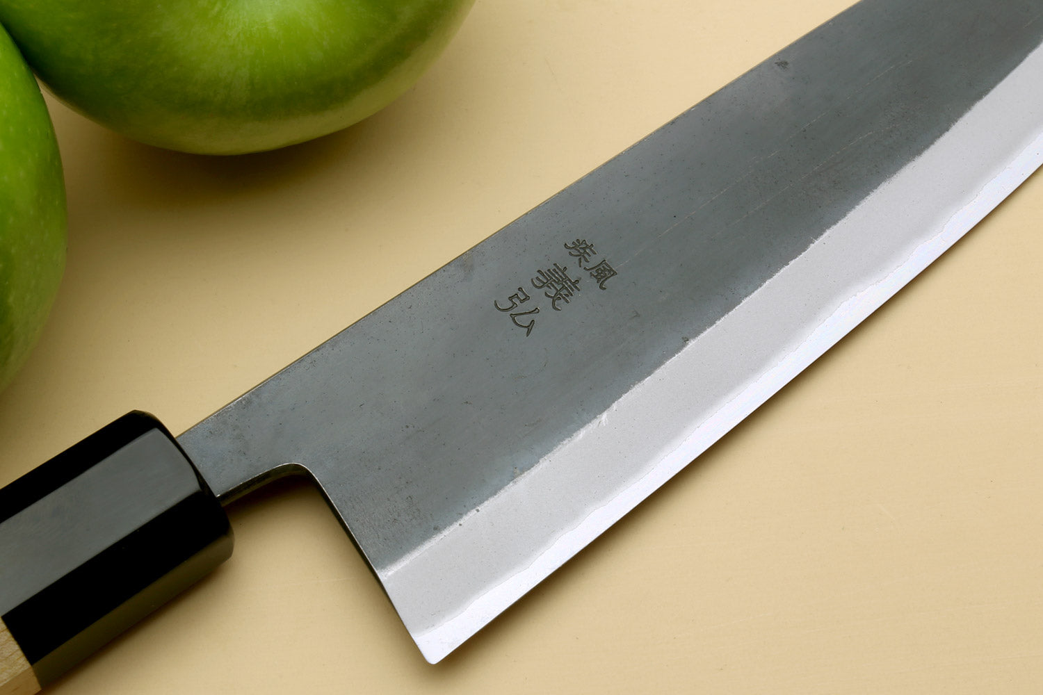 Santoku knife blade close-up with stamped markings and black bolster