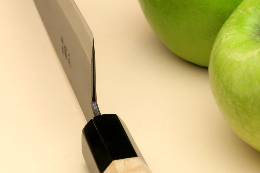 Santoku knife heel close-up with black bolster and light wood handle
