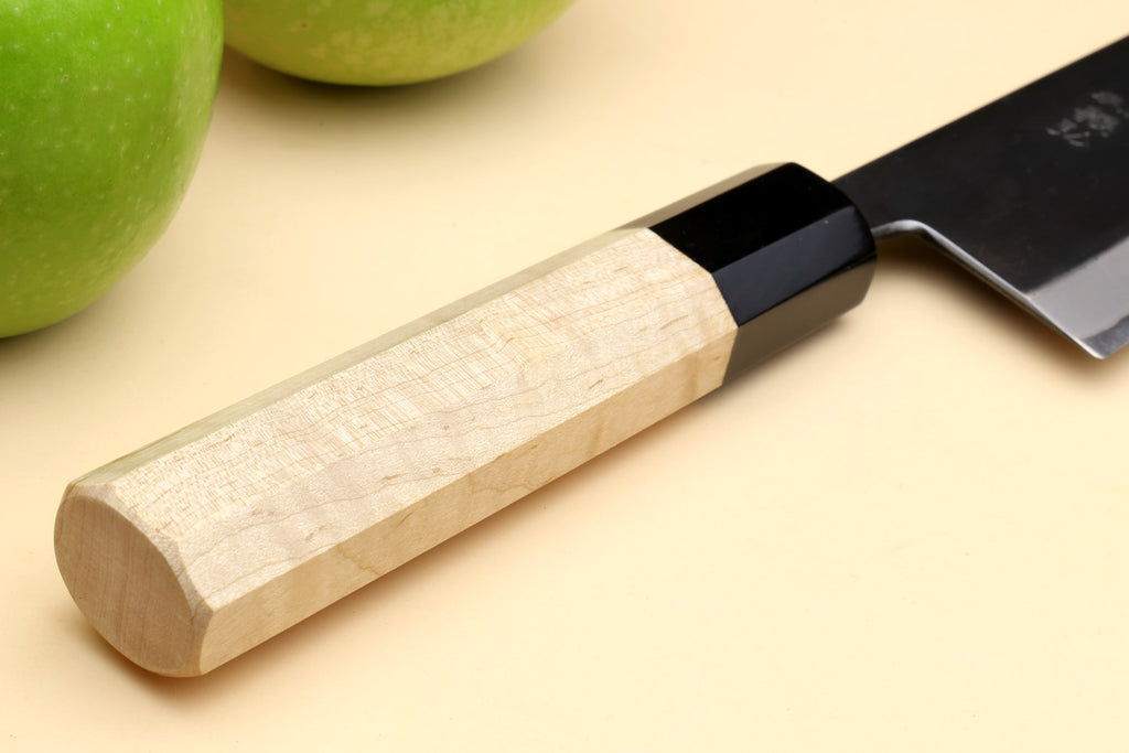 Santoku knife handle close-up with black bolster and partial blade