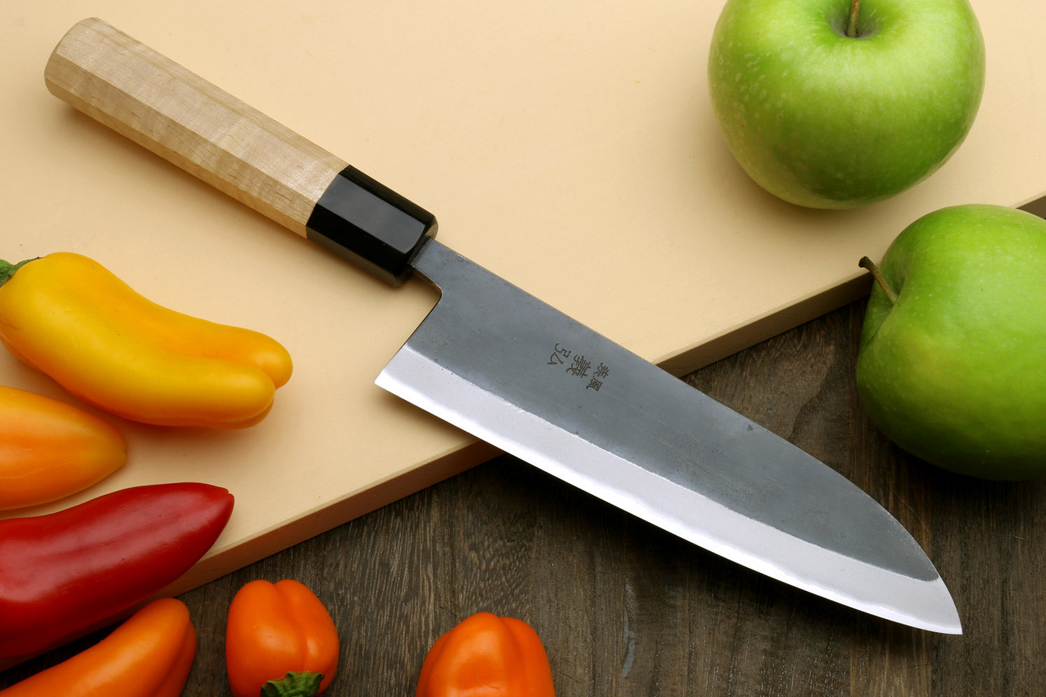 Santoku knife with stainless blade, black bolster, and light wood handle