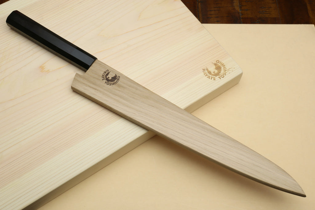 Sujihiki slicer knife with ebony handle and silver blade resting with wooden cover.