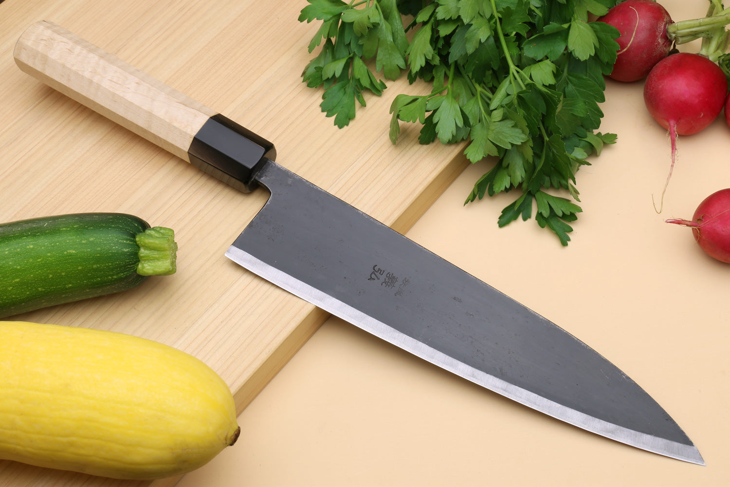 Gyuto chef knife with dark blade and pale camphor wood handle