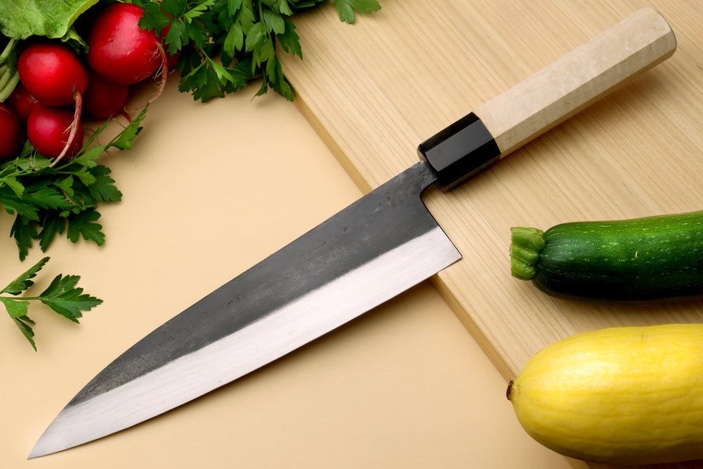 Gyuto chef knife with dark blade, pale camphor wood handle, pointed tip