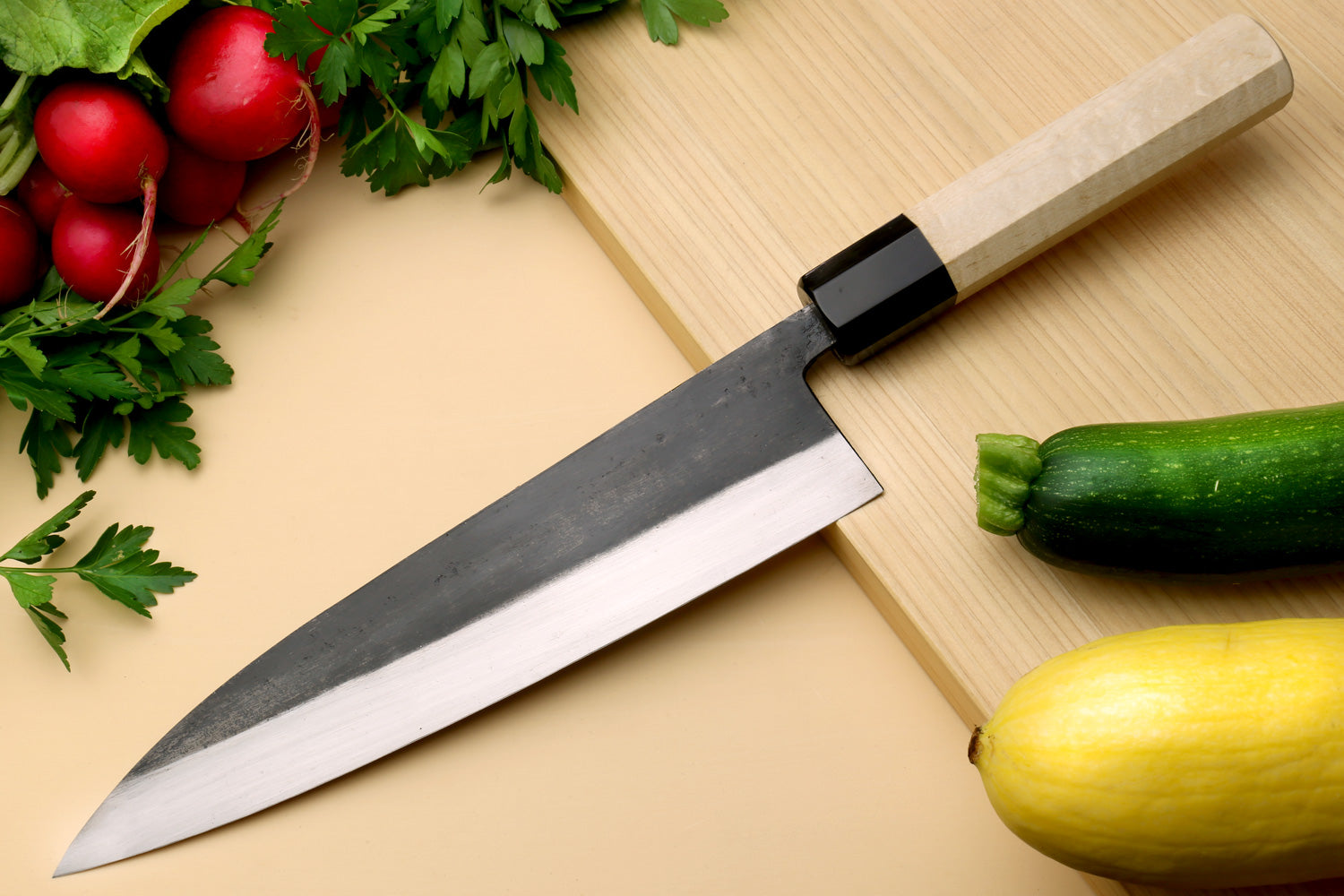 Gyuto chef knife with dark blade, pale camphor wood handle, pointed tip