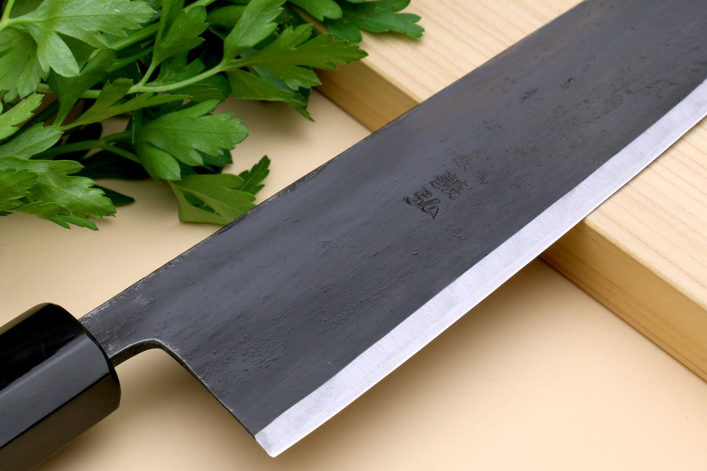 Gyuto chef knife close-up: dark blade with cutting edge and mark near heel