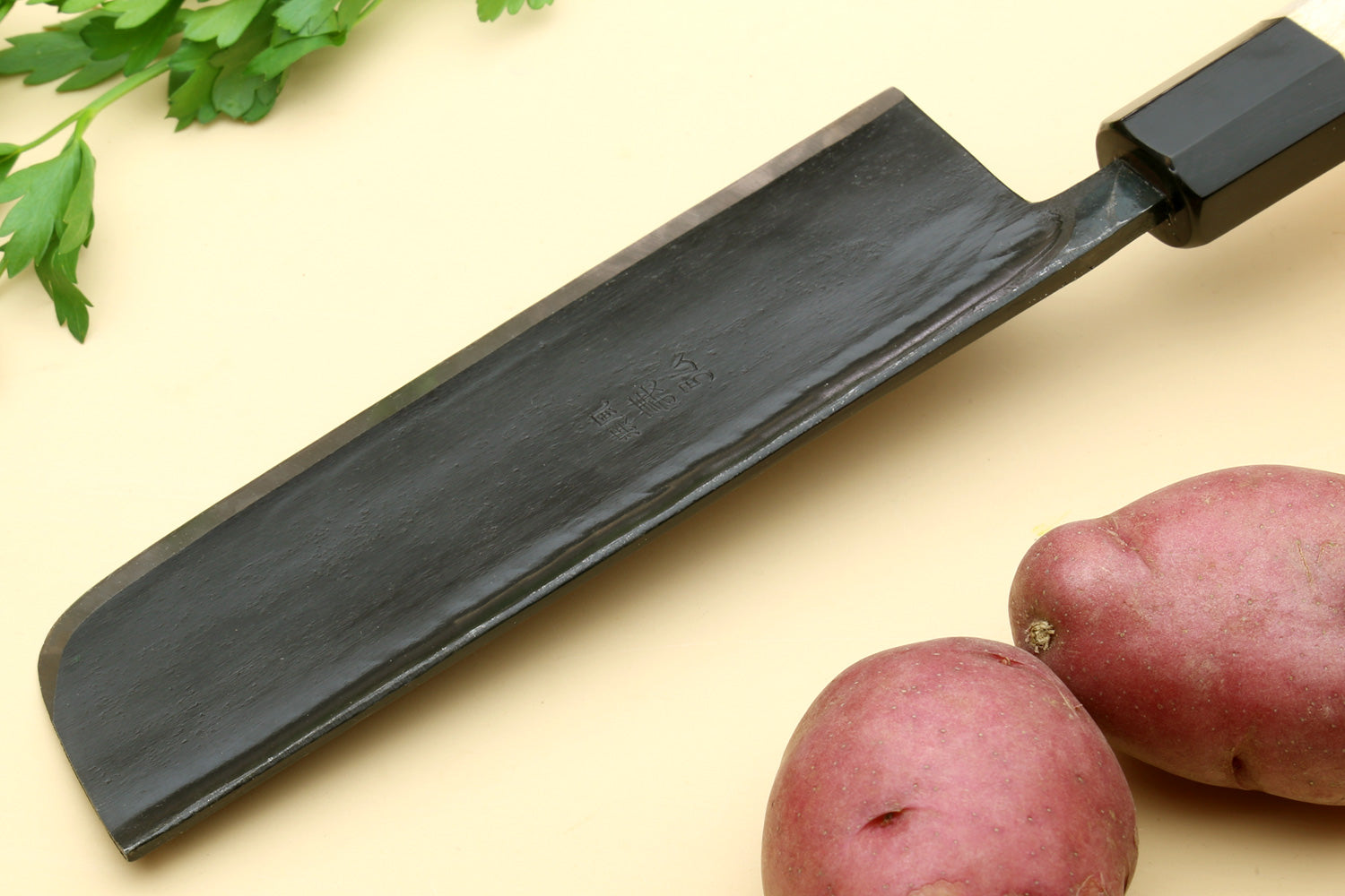 Nakiri vegetable knife side view: dark steel blade and light camphor handle